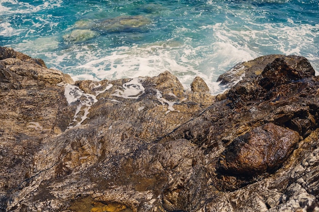 青い地中海の素晴らしい景色日当たりの良い岩が泡と水しぶきで波を打ちます波は岸の岩に衝突します