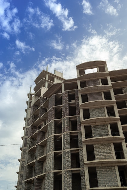 Woningbouw met meerdere verdiepingen in aanbouw en kraan op een achtergrond van blauwe lucht