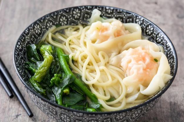 Wonton soup in a bowl on wooden table Chinese food