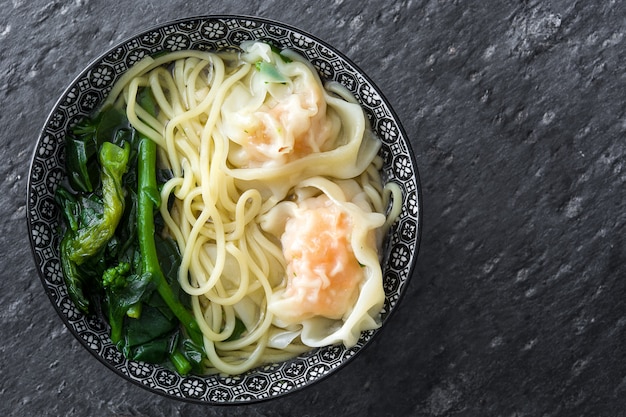 Wontonsoep in een kom op zwarte lei. chinees eten