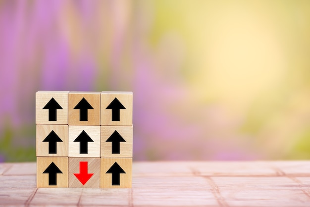 Wood block red arrow pointing the opposite way disruptive from the black arrows on table wooden.