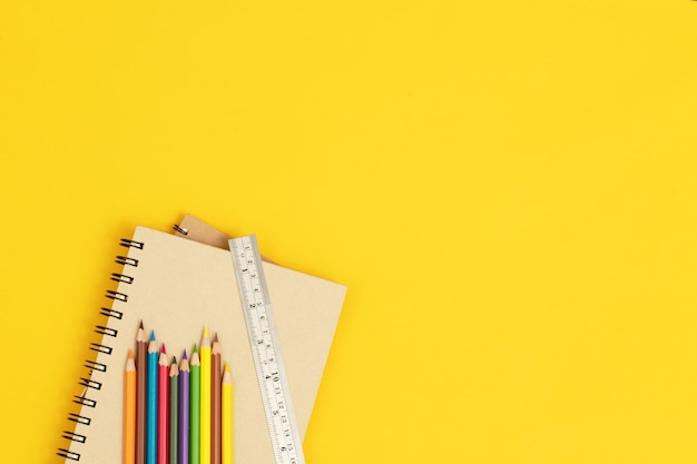 Wood color and ruler placed on a notebook and yellow background.