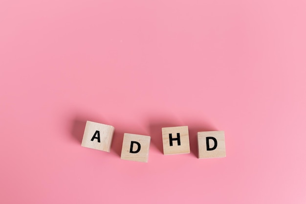 Photo wood cube block abbreviation of adhd on pink table attention deficit hyperactivity disorder adhd concept