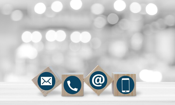Wood cube with Phone Email and Post Icons on white table over blur bokeh light background copy space Contact us