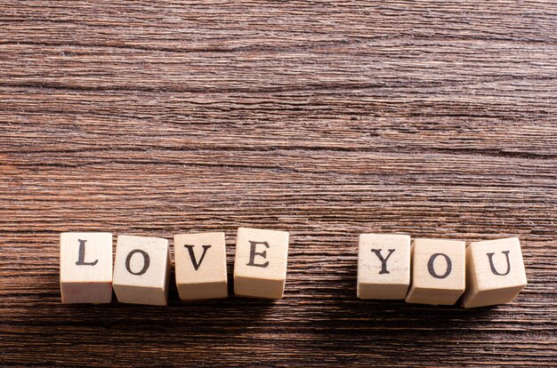 Wood cubes with inscription LOVE YOU on wooden table. 