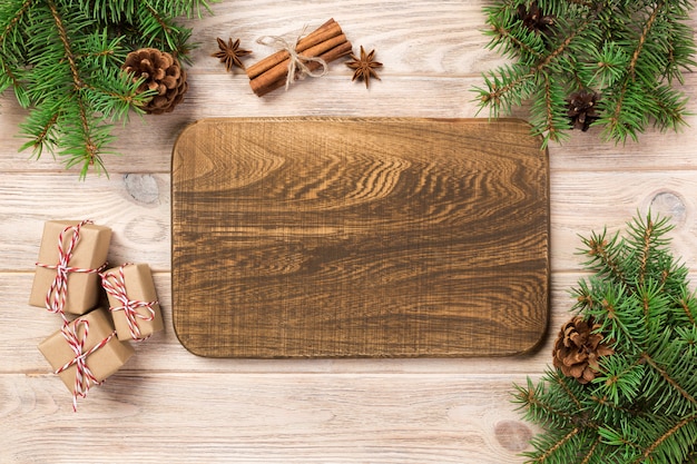 Деревянная разделочная доска на предпосылке таблицы с украшением рождества, круглой доской.