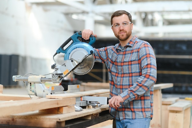 Wood cutting table with electric circular saw Professional carpenter in uniform cutting wooden board at sawmill carpentry manufacturing Sawing machine