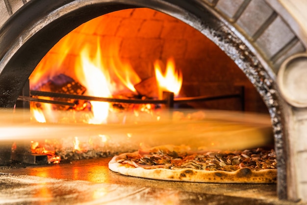 Foto pizza tradizionale con forno a legna per pizza ristorante che produce pizza classica con forno in pietra a legna