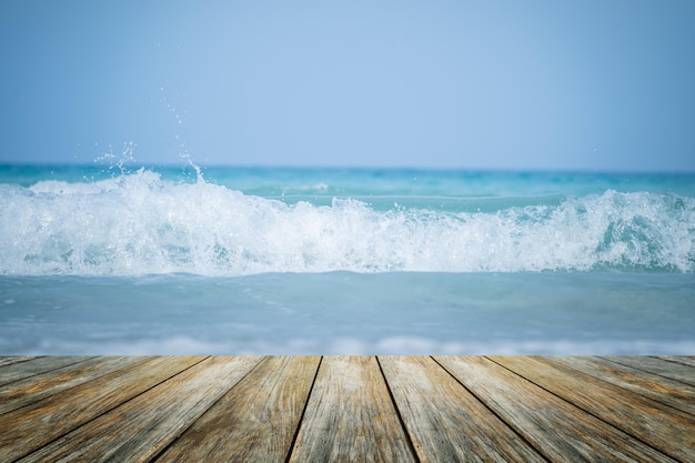 Wood floor foreground on horizon tropical wave water sandy\
beach blur blue sea background with relaxing summer vacation with\
sunrise sun lighting view deck touching sunshine sky surf summer\
clouds