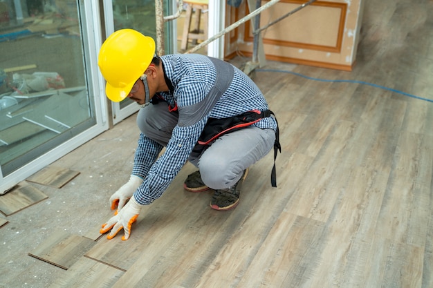 Wood flooring workers,construction worker installing new\
laminate wooden floor at house.