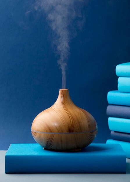 wood fragrance on the desk table with natural oils essence vapor, with blue and teal colored books