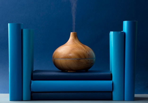 Wood fragrance on the desk table with natural oils essence vapor, with blue and teal colored books