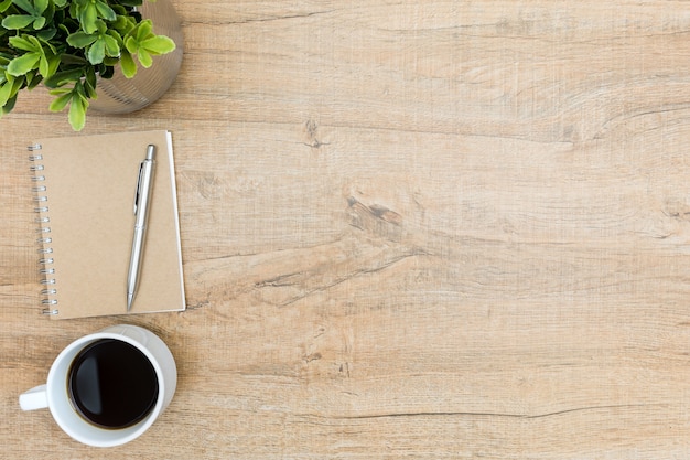 Wood hipster desk table with notebook and pen, coffee and tree pot. 