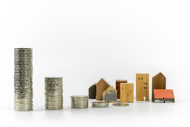 Modello della casa di legno e fila di soldi di moneta su fondo bianco, isolato,