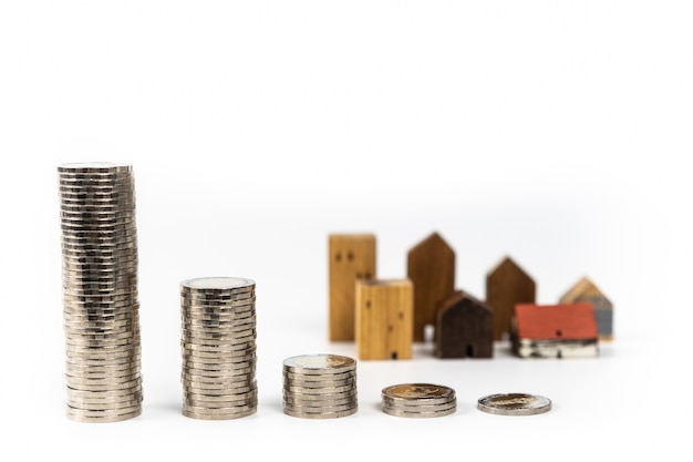 Modello della casa di legno e fila di soldi della moneta su fondo bianco