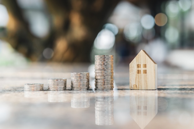 Wood house model and row of coin money on white background,