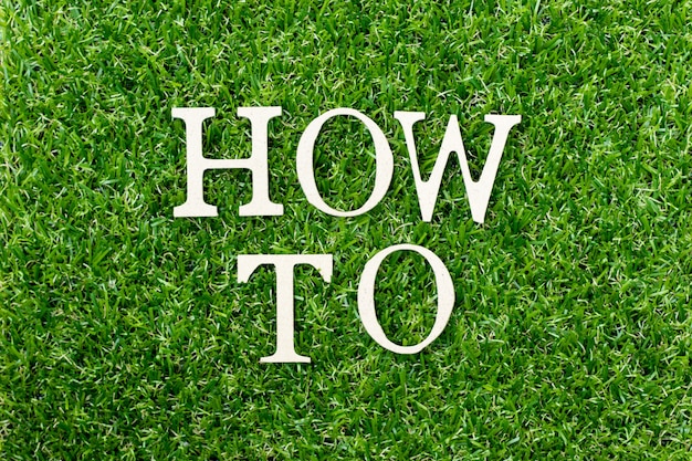 Wood letter in word "how to" on green grass