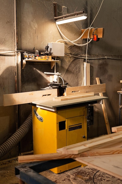 Wood milling machine with yellow rip fence in carpentry workshop in sunlight