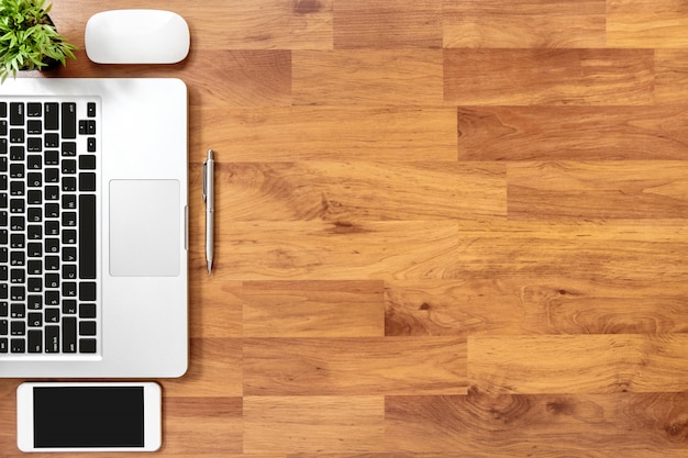 Wood office desk table with laptop computer, smartphone and supplies. Top view, flat lay background with copyspace