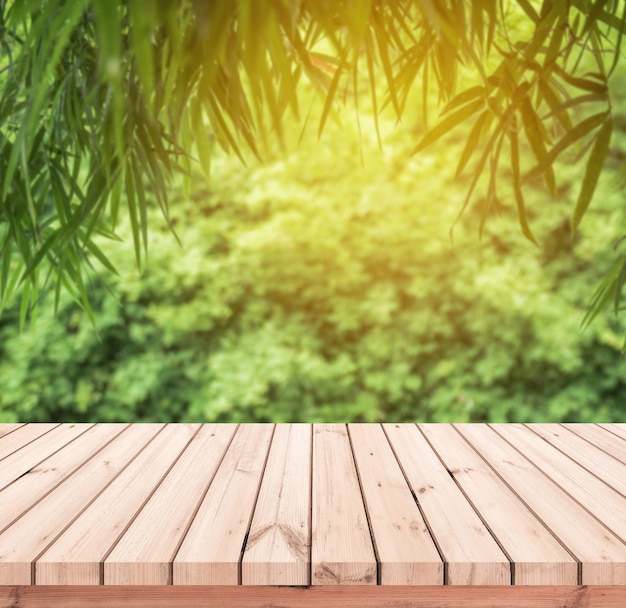 Wood plank with abstract natural blurred bamboo leaves background for product display