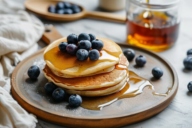 Wood plate of delicious pancakes with fresh blueberries and syrup on grey table