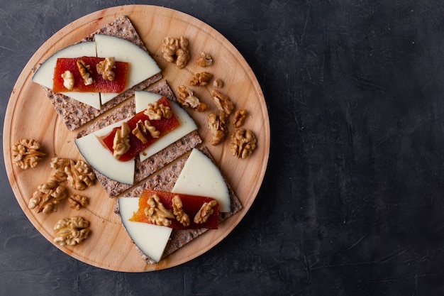 Деревянная тарелка с сырными орехами и желе из айвы поверх тостов Здоровое питание