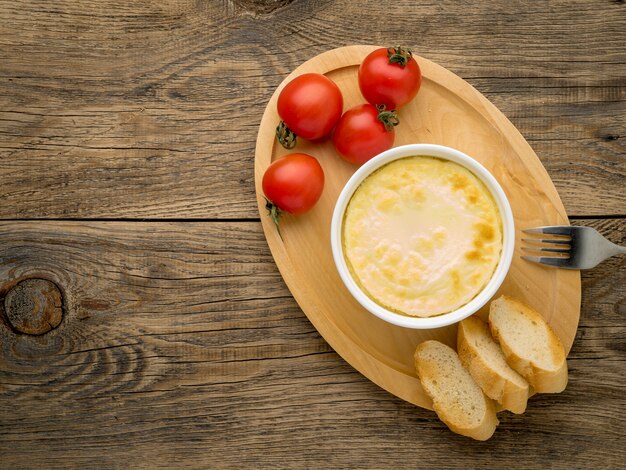 Wood plate with oven-baked omelet of eggs and milk, with  tomatoes and toast 