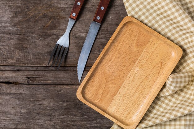 Piatto di legno con il coltello da bistecca su fondo di legno
