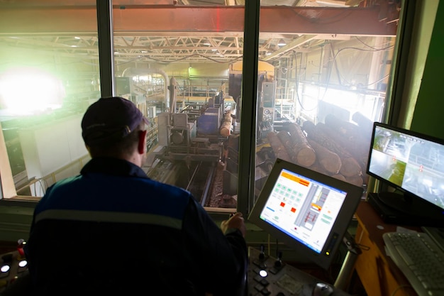 Photo wood processing industry wood cutting shop worker at the computer controls the cutting of wood