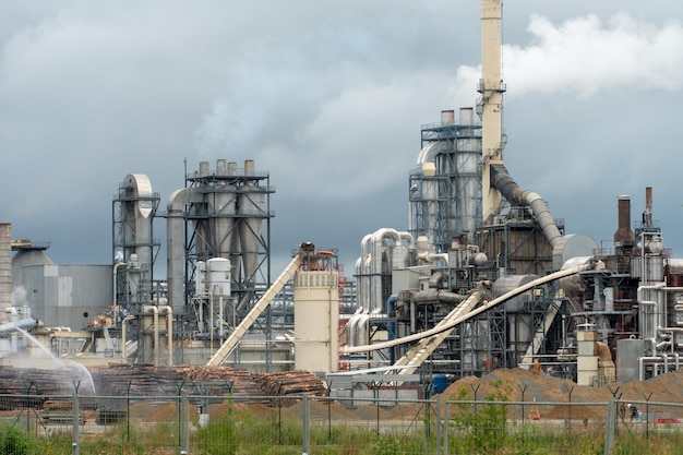 Wood processing plant against the background of gray clouds\
white toxic smoke comes out of factory chimneys utopian landscape\
environmental pollution an environmental disaster