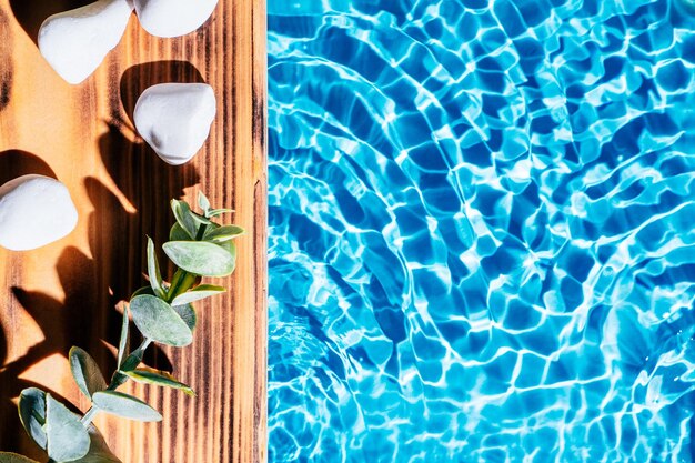 Wood sand board with hot white salt stones and twig natural eucalyptus Blue transparent reflect wave water Copy space