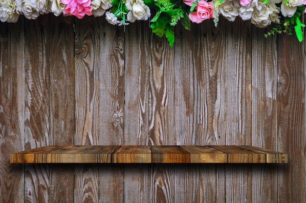 The wood shelf is on the old wooden planks with roses decorated on top.