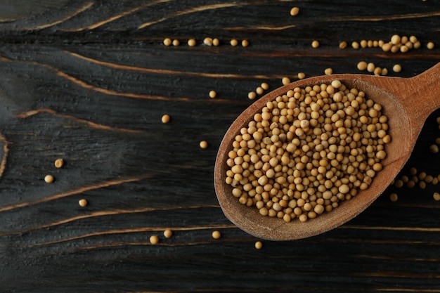 Wood spoon with mustard seeds on wooden background