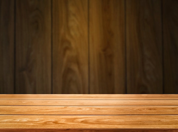 Tavolo in legno davanti alla sfocatura dello sfondo della parete in legno per il modello di visualizzazione del prodotto.