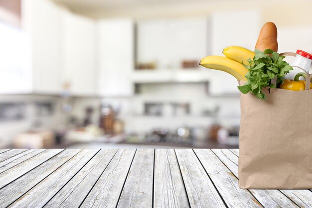 Wood table top and bag with products on blurred kitchen background