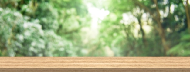 Foto piano tavolo in legno e sfocatura foresta verde per le dimensioni del banner di montaggio del prodotto e del display