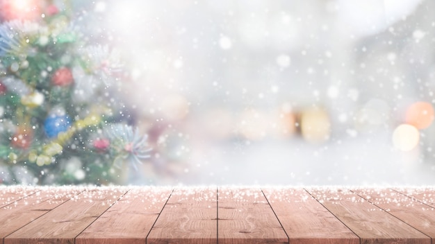 Photo wood table top on blur with bokeh christmas tree background with snowfall