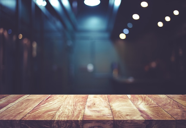 Wood table top on blurred of counter cafe shop with light bulb background