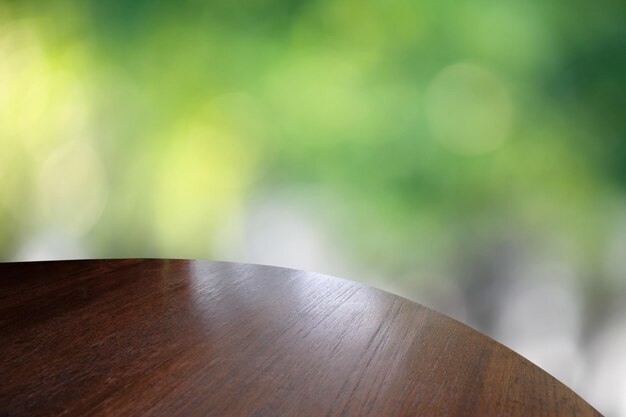 Il piano del tavolo in legno su sfondo verde bokeh può essere utilizzato per il montaggio o visualizzare i tuoi prodotti