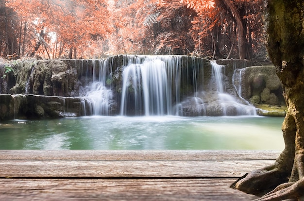 Wood table top on waterfall autumn leaf scene