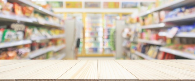 Wood table top with Supermarket convenience store aisle shelves interior blur for background