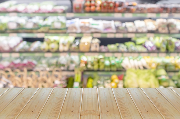 Wood table top with vegetables on grocery store shelves blurred background