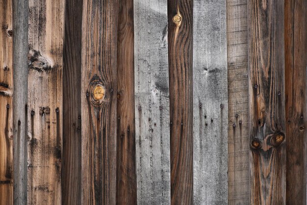 Wood texture wallpaper background, vintage darkened fence. Gray and brown boards with rusty nails. High quality photo