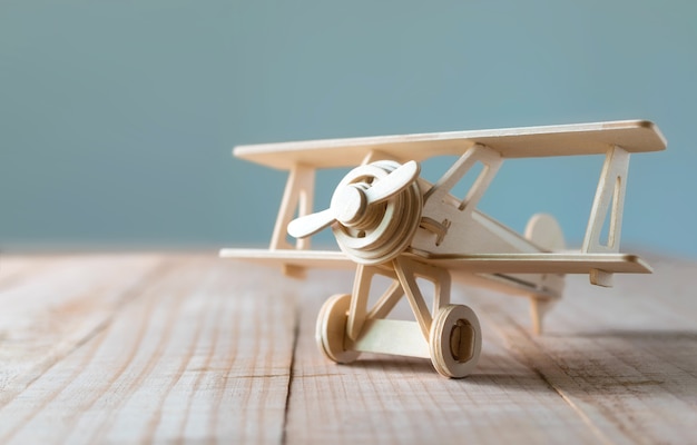 Wood toy airplane on wood table with blue clean background.