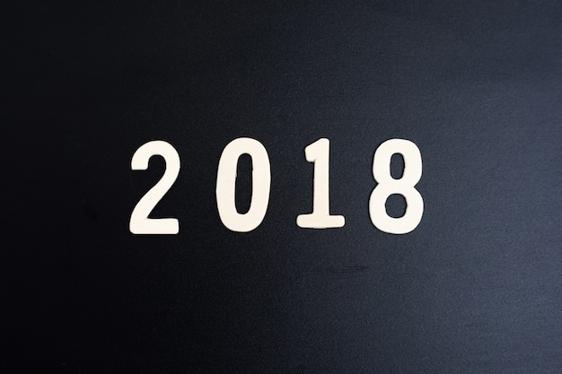 wood word of 2018 numbers lie on wooden table and black background. 