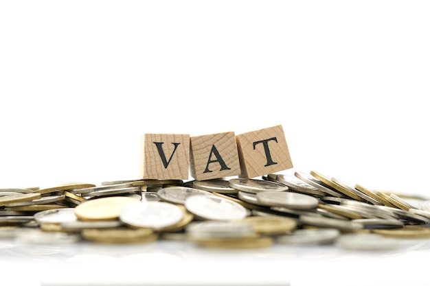 Wood word VAT is placed on a pile of coins.