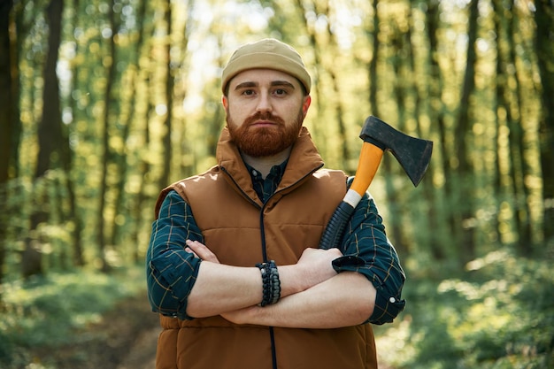 Woodcutter is standing Bearded man is in the forest at daytime