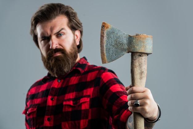 Woodcutter in a plaid shirt Lumberjack brutal bearded man in red checkered shirt concept of shaving halloween man holds an ax in his hand bearded lumberjack with an axe selective focus