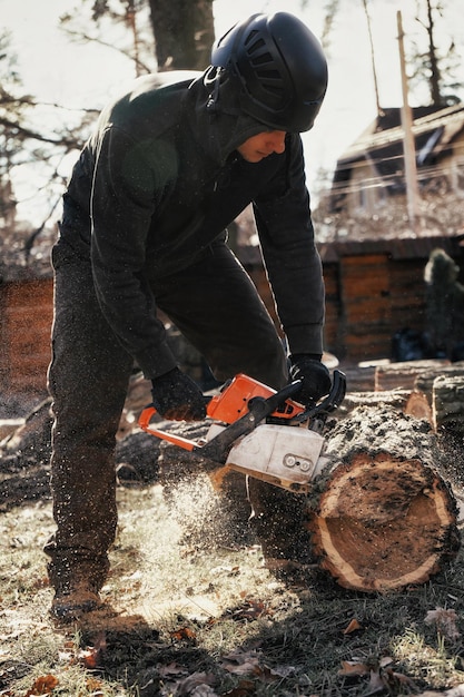 Woodcutter saws tree trunk with chainsaw Sawdust flies from chainsaw