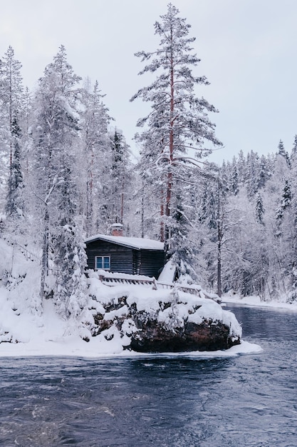 wooden abandoned house in a winter park on the river bank in Lapland, Finland